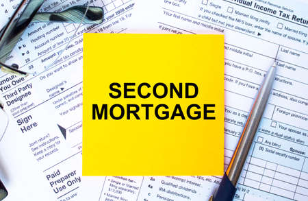 Financial concept. Text Second Mortgage on note paper with the US IRS 1040 form, pen and glassesの写真素材