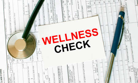 Text Wellness Check on the white card with the stethoscope, pen and medical documents. Medical concept photoの写真素材