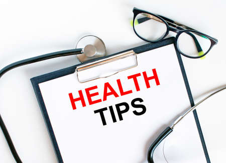 Text Health Tips in the folder with the stethoscope and glasses. Medical concept photoの写真素材