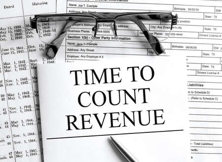 Paper with text Time To Count Revenue on a financial table with eyeglasses and metal pen. Financial and concept photoの写真素材