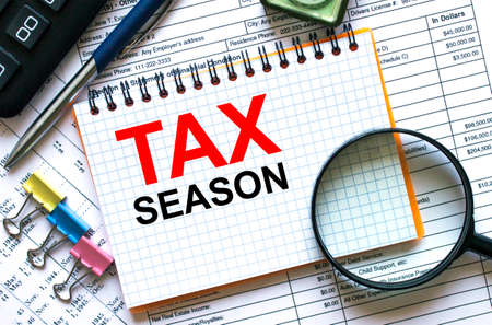 Text Tax Season on notepad with calculator, clips, pen on financial report. Financial and business concept photoの写真素材
