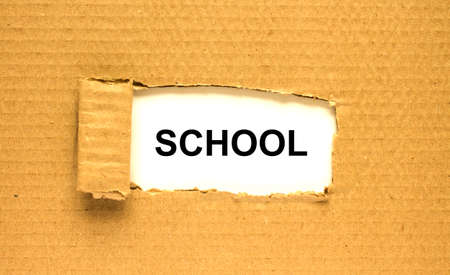 The word School appearing behind torn brown paper. Can be use as a concept photoの写真素材