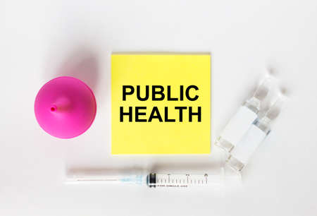 Yellow sticker with text Public Health on a white background with syringes, enema and ampoule. Medical concept photoの写真素材