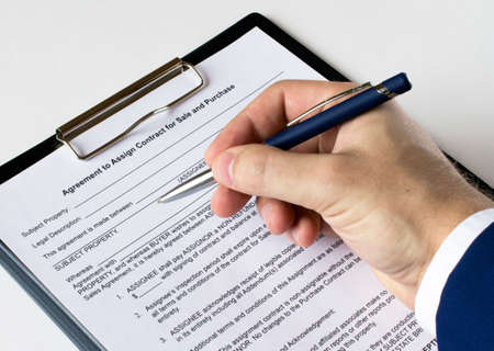 A man's hand with a pen signs a contract in a folder. Business conceptの写真素材