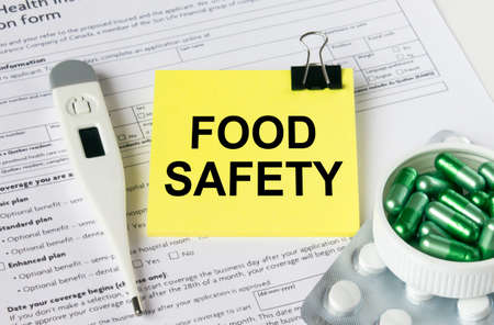 A yellow sticker with the text Food Safety is on the health insurance form with pills and an...