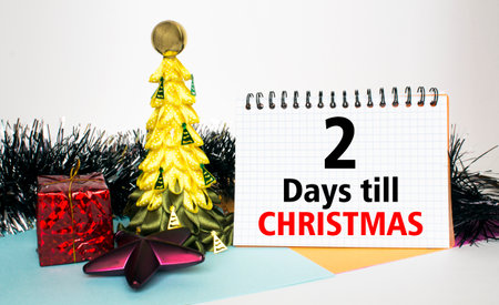 Christmas tree decorated with toys and tinsel, gift boxes and Notepad with text 2 Days till...