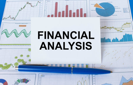 Business card with text Financial Analysis laying on financial graphs with blue pen. Business and...