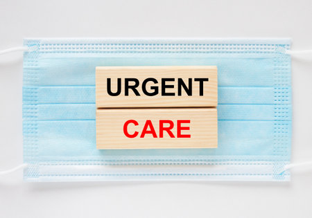 Wooden blocks with text Urgent Care lying on the mask. Medical conceptの写真素材