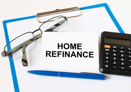 A business card with text Home Refinance lying on a clipboard with a blue pen eyeglasses and a calculator. Business concept.の写真素材