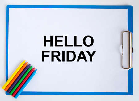 Colored pencils and clipboard with a text Hello Friday. Concept photoの写真素材