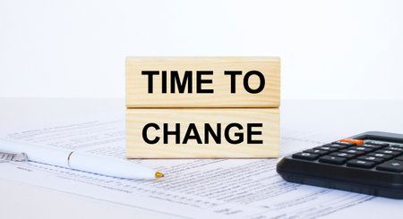 Time To Change text concept written on wooden cubes blocks lying on a light table next to calculator and penの写真素材