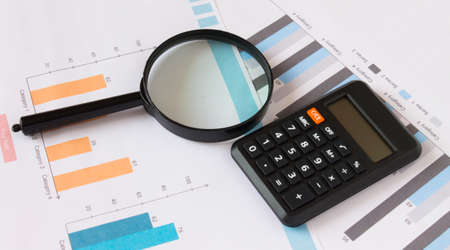 Calculator with magnifying glass on the diagrams. Business and financial concept