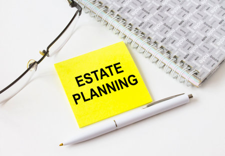 Text Estate Planning on a yellow sticker lying near notepad with eyeglasses and pen. Could be for business, financial and marketing conceptsの写真素材