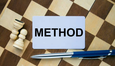 Business card with text Method on a chess board with pen. Concept photo