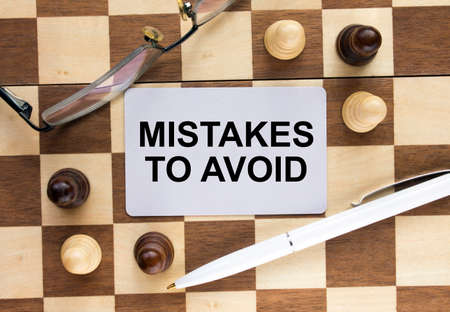 Business card with text Mistakes To Avoid on a chess board with pen and eyeglasses. Concept photoの写真素材