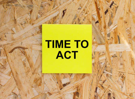 Yellow Sticker with text Time To Act on the wooden background. Concept photoの写真素材