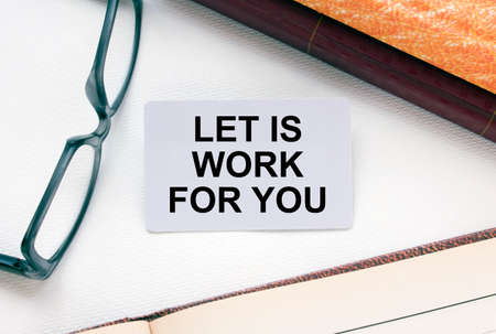 Text Let is Work For You on a business card lying next to notepad with eyeglasses and text documents. Business conceptの写真素材