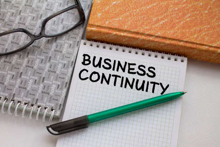Notepad with text Business Continuity with another notepad pen and eyeglasses. Top viewの写真素材