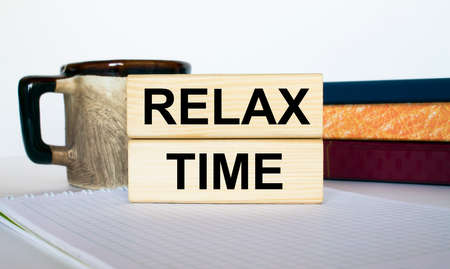 Wooden blocks with text Relax Time on a stack of notebooks and cup of coffee. Concept photoの写真素材