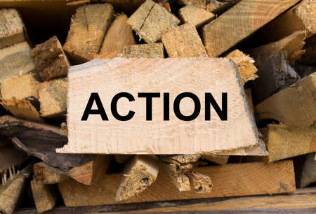 Wall firewood. Background of dry chopped firewood logs in a pile and plate with text Action. Concept photoの写真素材