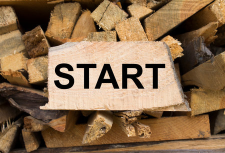 Wall firewood. Background of dry chopped firewood logs in a pile and plate with text Start. Concept photoの写真素材