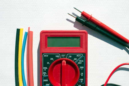 Multimeter with text on display and heat shrink insulation on white background. Construction and repairの写真素材