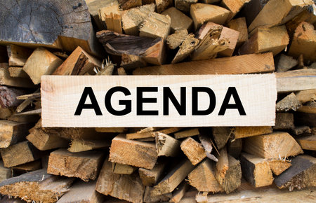 Wall firewood. Background of dry chopped firewood logs in a pile and plate with text Agenda. Concept photoの写真素材