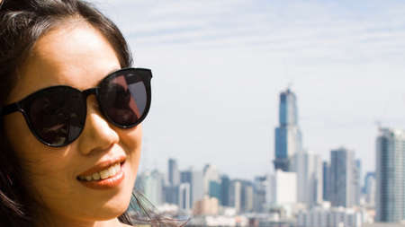 Young asian woman smiling happy on the city background wearing sunglassesの写真素材