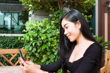 Young Asian Girl using smart phone in the garden. Can be use as concept photoの写真素材