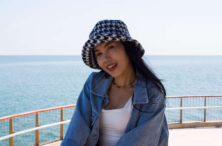 Beautiful asian woman with hat on the sea. Can be used as concept photoの写真素材