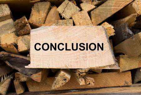wall firewood. Background of dry chopped firewood logs in a pile and plate with text Conclusion. concept photoの写真素材