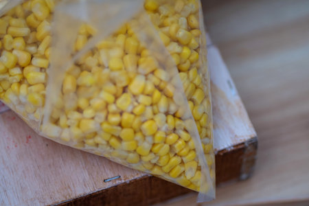 Yellow Corn Kernels inside Transparent Plastic Bag on Wooden Table Close Upの写真素材