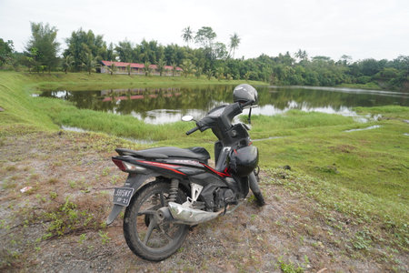 Black Cub Motorbike on Beautiful Green Scenery near Lakeside Landscapeのeditorial素材