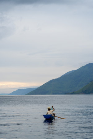 view of the horizon of lake toba in the morning with cloudy weather with a fisherman in the middle...