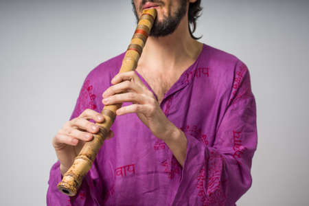 The musician who plays ethnic instruments. Man playing the Japanese flute. A young man in traditional Indian clothingの写真素材