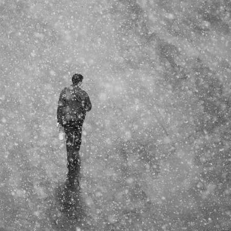 Large flakes of snow fall on the walking man. Artistic photography with snowの写真素材
