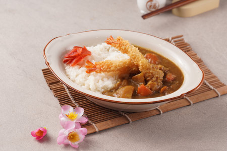 Japanese curry rice with chicken and vegetables in a bowl on a tableの写真素材