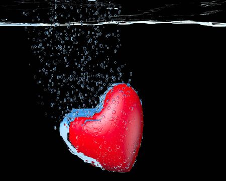 heart dropped into water over black backgroundの写真素材