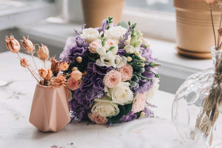 Brides wedding shoes with a bouquet with roses and other flowers on tha arm chair niceの写真素材