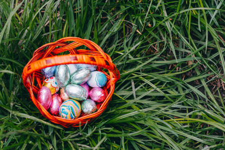 Chocolate Easter eggs in basket on green grass background.の写真素材