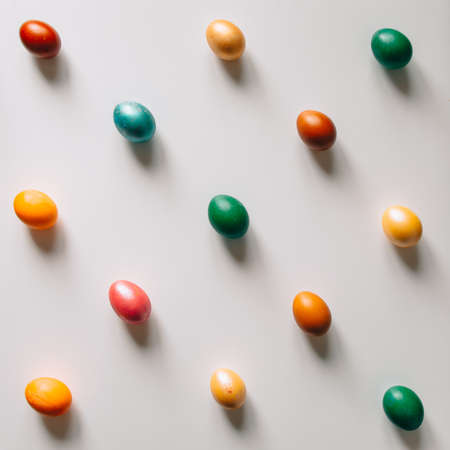 Small multi-colored Easter eggs on the kulich, festively decorated with colorful painted eggs paint, backgroundの写真素材