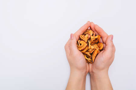 Female hands with sliced dried garden apples. Dried fruits. Healthy, natural foods. White background. Close-up. niceの写真素材