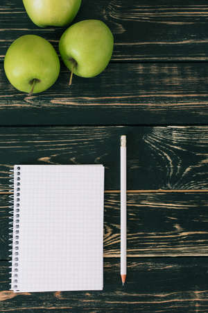 Home workplace. Black wooden table. Home Office. Student place. Fresh green apple. Niceの写真素材