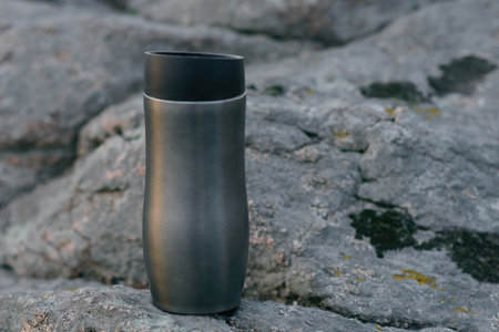Tourist mug on the background of mountains, stones and a river in which the sunset and clouds are reflected. Travel, hiking, sports, lifestyle healthy concept.の写真素材