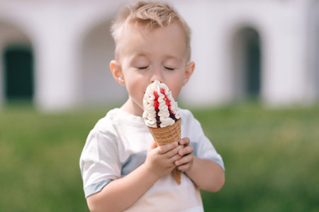 Portrait of a little boy. A baby eats a delicious ice cream cone. happy child. summer dayの写真素材