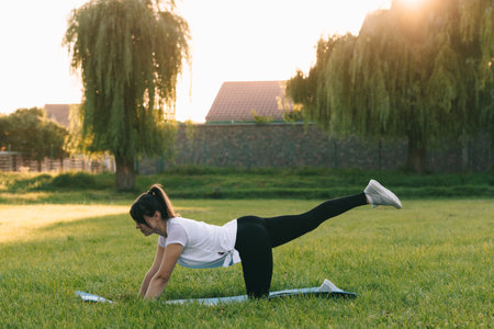 A girl with a sporty figure learns to do yoga in nature, assana. Sports on the background of the sunset. Summer evening.の写真素材