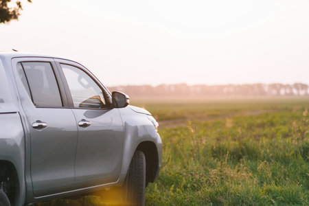 A silver truck is parked in a grassy field under the clear sky.の写真素材