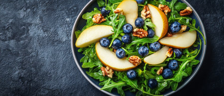A vibrant arugula salad topped with fresh blueberries, sliced pears, and walnuts is beautifully arranged on a dark surface, perfect for a nutritious breakfast.の素材