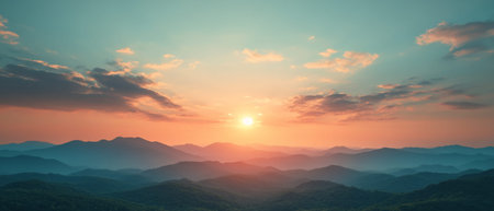 A stunning sunset bathes the mountains in warm hues, as the sun dips below the horizon. The tranquil landscape showcases layers of hills under a vibrant sky.の素材