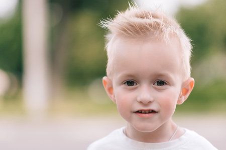 A fair-haired boy on a blurred summer background makes different emotional faces. Children's...